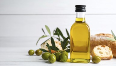 Bottle of fresh olive oil with branch with green olives and ciabatta, closeup, white wooden table,