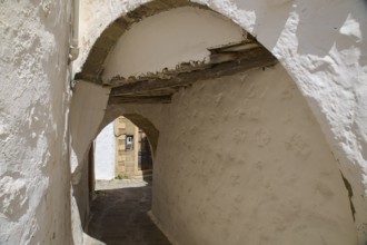 Narrow, shady alleyway with stone arches and a passageway in a historic setting, Chora, UNESCO