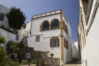White house with striking balcony and brick details under a clear blue sky, Lion's Alley, Captain's