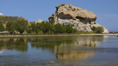Elevated rock with its reflection in the calm lake on a sunny day, Seasonal salt lake, Rock of