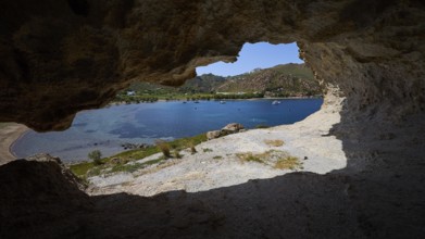 View from a cave onto a blue sea with rocks and coastal landscape in the sunlight, Petra beach,