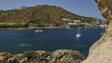 Coast with houses and boats on the calm sea, surrounded by hills and rocks, cave, rocks of