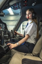 Confident female pilot sitting in the cockpit of a small airplane, adjusting controls and getting