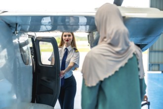 Female pilot welcoming a muslim passenger aboard a small airplane, embodying hospitality and