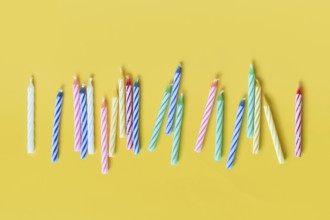 Colorful birthday candles in a row on yellow background