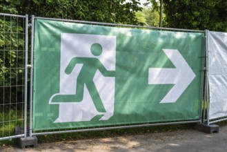 Bauzaun, Absperrung, Barriere mit einem Piktogramm einer flüchtenden Person, Symbos für Notausgang,