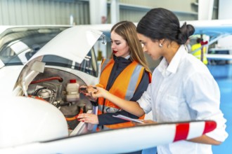Two female engineers in a hangar inspecting an aircraft engine, focusing on maintenance and safety