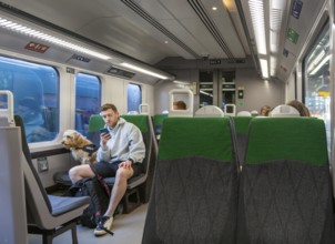 Passenge on train with his sitting dog on a seat, UK