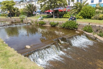Dawlish Water river flowing through park gardens in town centre, Dawlish, south Devon, England, UK