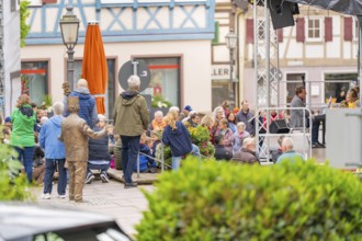 Lively market square with an event, many people gathered in front of half-timbered houses, family