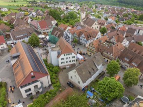 Aerial view of a village with historic architecture, numerous red roofs and a central church,