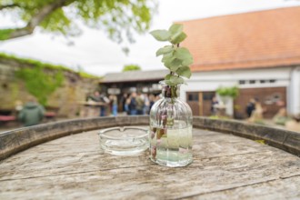 Wooden table with decorative glass bottle in a relaxed outdoor area at an event, family celebration