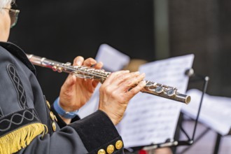 Musician playing the flute during a performance, in uniform with sheet music, family party in