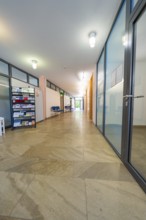 Long, modern hallway with glass doors, brochure rack and bright light, family party in Neubulach,