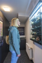 Woman looking with interest at a display case with stones in a museum, family festival in