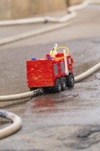 Small red toy fire engine examined on a wet road, family party in Neubulach, Calw district, Germany