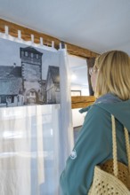 Woman looking at historical photograph in a room with wooden elements, family celebration in