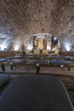 Vaulted cellar with sculpture, surrounded by stone walls and illuminated, sacred ambience, registry