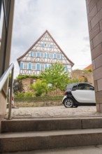 Traditional half-timbered house in the old town centre with a car in the foreground and steps,