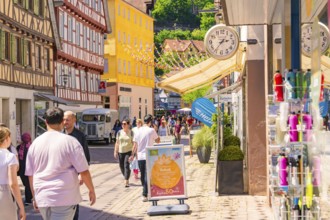 Lively street with half-timbered houses and shops, full of pedestrians on a sunny day, Calw railway