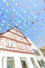 Colourful half-timbered house with flags under a bright blue sky, Calw station festival, Black