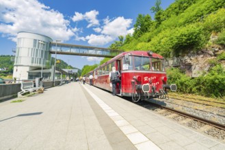 Red train stands on the platform in bright daylight, Calw railway station festival, Black Forest,