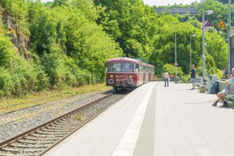 Red train approaches a sunny railway station surrounded by nature, Calw station festival, Black