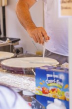 Person preparing crepe batter at a market stall, Calw railway station festival, Black Forest,
