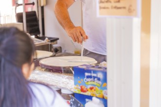 Man preparing crepes in a market stall with Capri-Sun in the background, Calw railway station