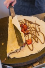 A crêpe is topped with chocolate and strawberries and rolled up, Calw railway station festival,