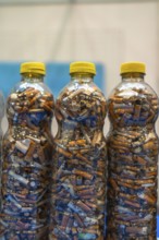 Plastic bottles are filled with discarded cigarette butts, highlighting the pervasive issue of
