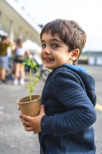 Young boy holding a small plant in a biodegradable pot, symbolizing environmental protection and