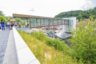 People standing on a modern bridge with city and green views, Zob extension with bridge
