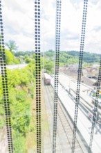View through a glass wall onto a railway line in a green environment in sunny weather, Zob