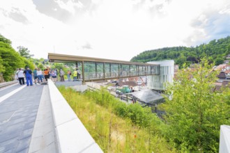 A group of people gather on a bridge overlooking a town, Zob extension with bridge construction for