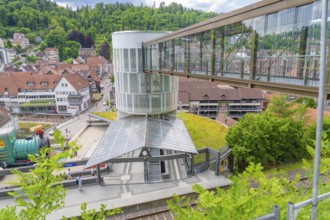 A railway station with a modern glass pedestrian overpass in a small green town, Zob extension with