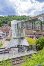 Modern pedestrian bridge over a railway station in a green, small town under a blue sky, Zob