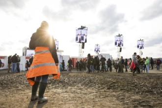 A festival visitor stands in front of a muddy area in the evening sun at the Rock am Ring Festival