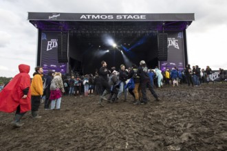 Festival visitors dance in the mud in front of the Atmos Stage at the Rock am Ring Festival on