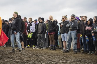 Festival-goers stand in the mud in front of the Atmos Stage at the Rock am Ring Festival on Sunday,
