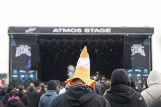 Festival visitors with a hat shaped like a cone in front of the Atmos Stage at the Rock am Ring