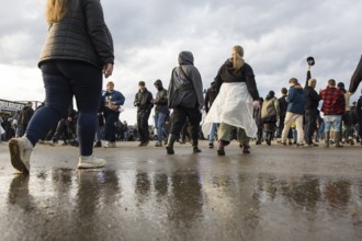 Festival visitors are reflected in a puddle at the Rock am Ring Festival on Sunday, Nürburgring