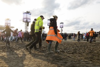 Festival visitors walk through mud in the evening sun at the Rock am Ring Festival on Sunday,