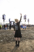 A festival visitor from Turkey poses in front of a muddy area in the evening sun at the Rock am