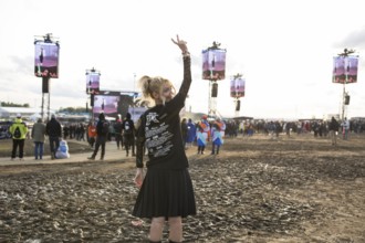 A festival visitor from Turkey poses in front of a muddy area in the evening sun at the Rock am