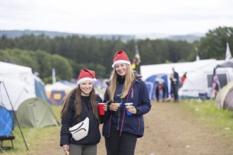 Joline and Lisa with Christmas hats on a campsite at the Rock am Ring Festival on Saturday,