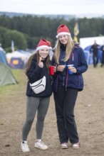 Joline and Lisa with Christmas hats on a campsite at the Rock am Ring Festival on Saturday,