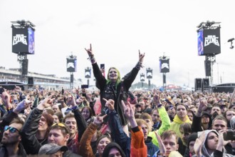 Festival visitor on shoulders with a French fries fork shaped like a hand at the Rock am Ring