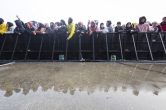 Festival visitors at the barrier are reflected after heavy rain at the Rock am Ring Festival on