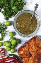 Tkemali sauce, made from green cherry plum, with ingredients on the table, tobacco chicken, top